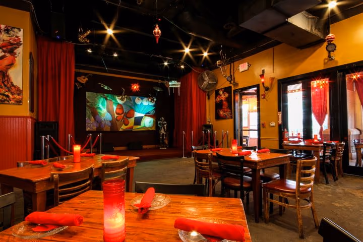 The dining room at Eclipse di Luna Dunwoody, with wooden tables, red accents, and a stage for live music