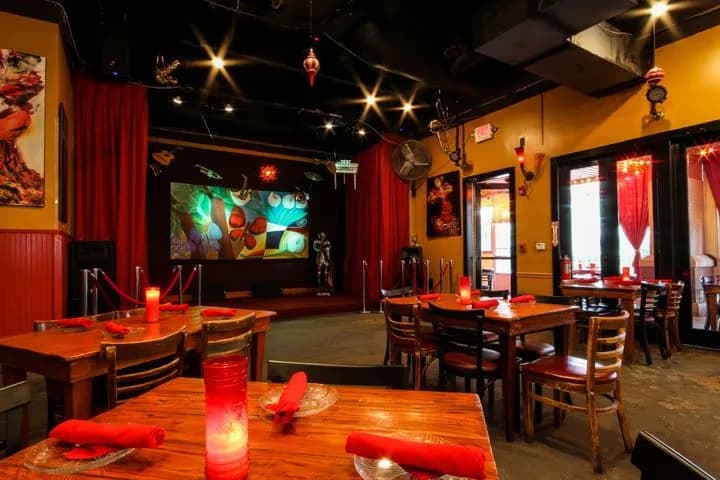 The dining room at Eclipse di Luna Dunwoody, with wooden tables, red accents, and a stage for live music