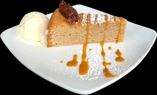 A slice of Tarta de Santiago dusted with powdered sugar, served with vanilla ice cream and a caramel drizzle
